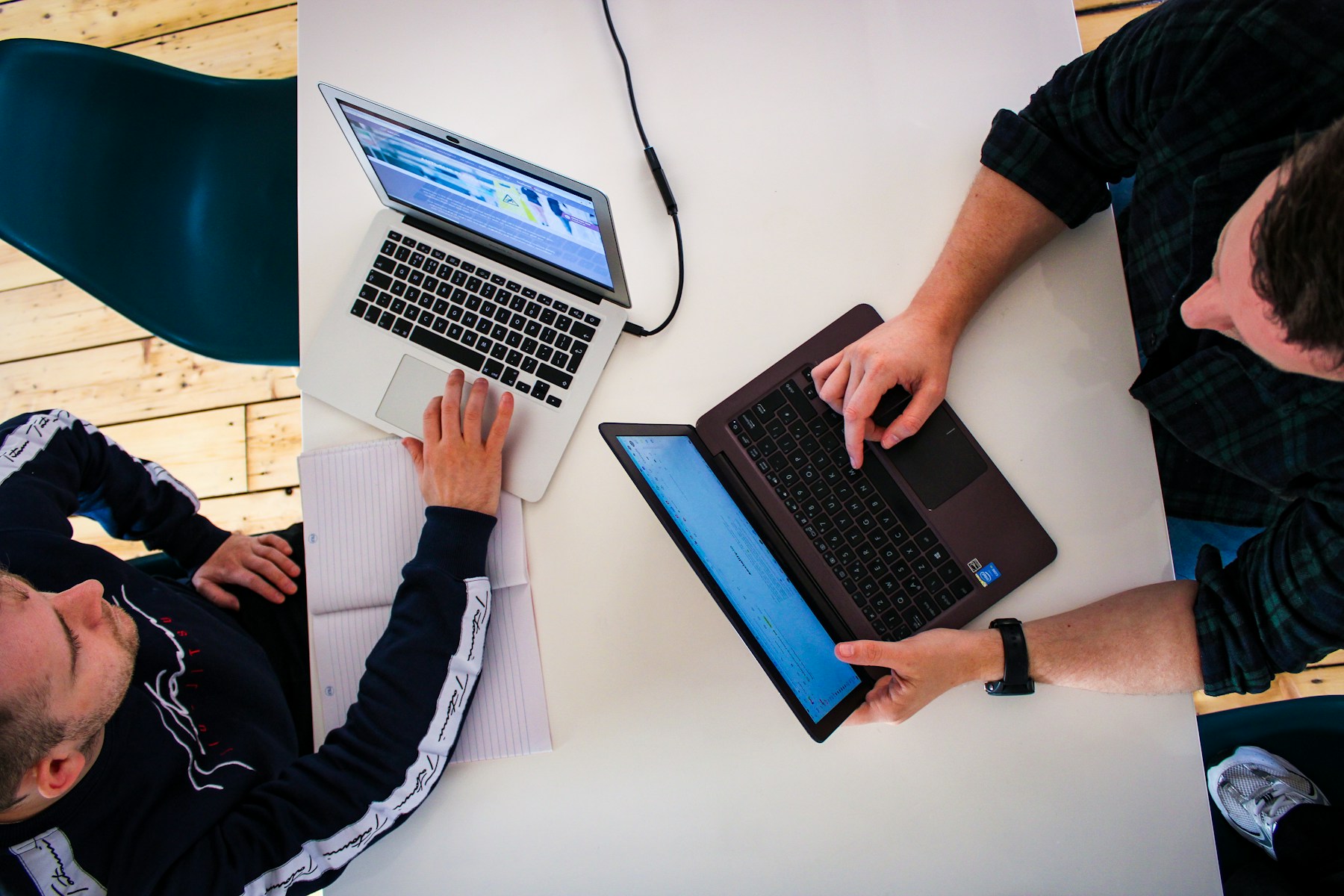 Two technology founders collaborating across laptops in a modern startup office